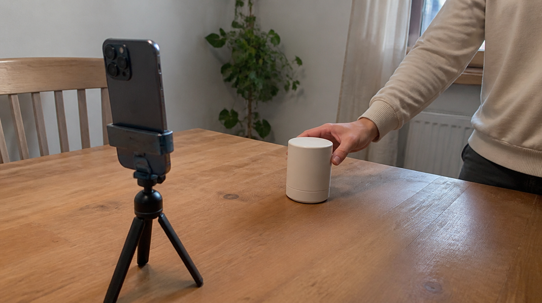 Mesa de trabajo real con un producto, fotos de referencia y un móvil preparado para grabar un vídeo